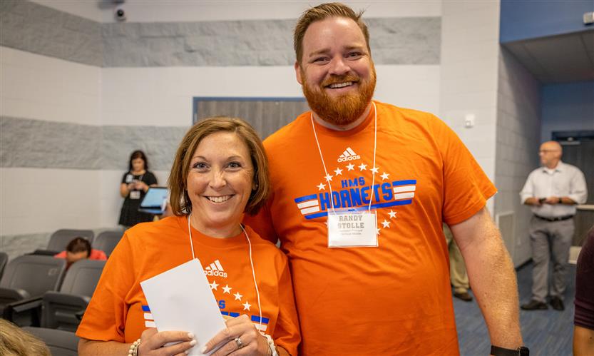 Two administrators smile while standing in the aisle of a theater